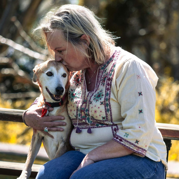 Woman kissing a dog on a wooden bridge with blurred natural background
